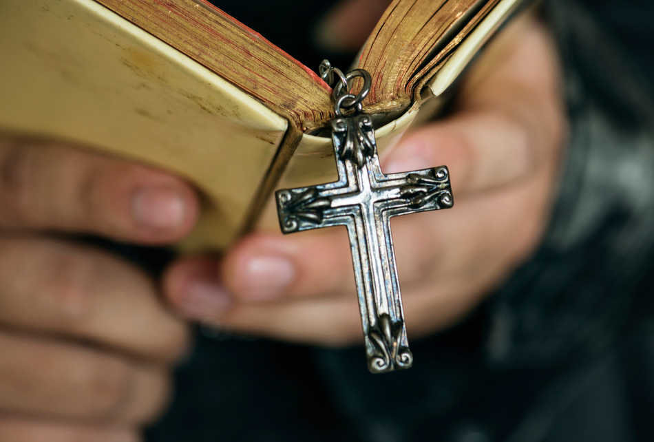 close-up-man-reading-bible-with-cross-hanging-religion-belief-concept (1)