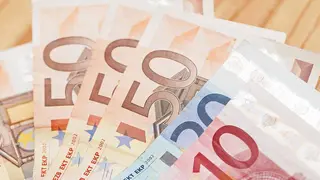 Heap of different euro banknotes on a wooden table