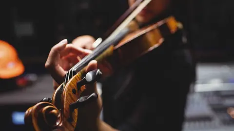 Female student playing violin in a studio