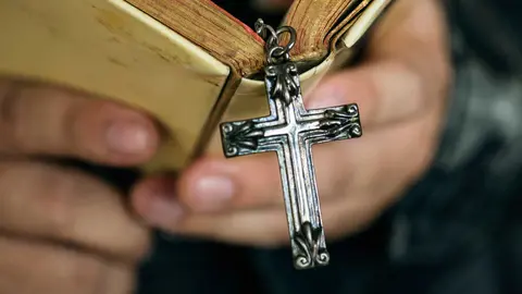 close-up-man-reading-bible-with-cross-hanging-religion-belief-concept (1)