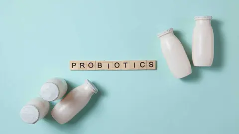 Bottles with probiotics and prebiotics dairy drink on light blue background. Bio yogurt with useful microorganisms. Production with biologically active additives. Fermentation and diet healthy food.